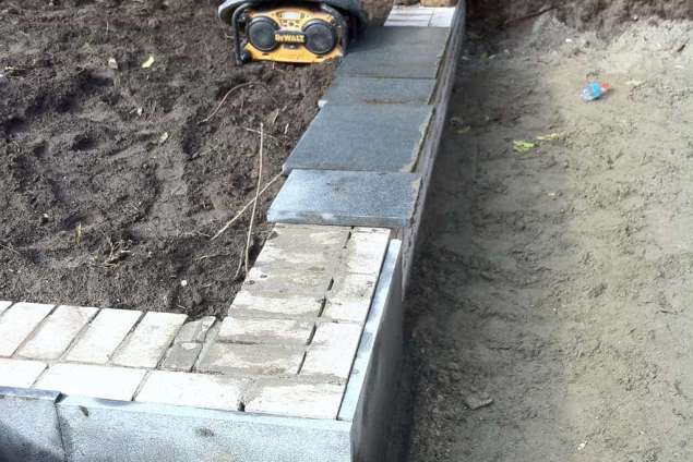 stellen tuinmuur voor hoogte en diepte in de tuin de tuinmuur wordt strak afgewerkt en bekleed met natuursteen, voorlijmen muur met voorlijm en dan beplakken met tegels Tilburg Eindhoven Breda Udenhout Den Bosch Reeshof Maaspoort, Utrecht